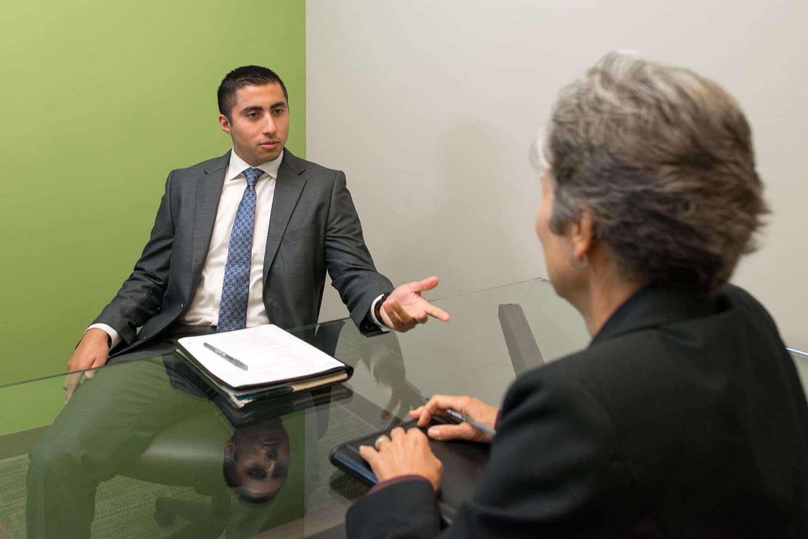 A candidate in a suit explaining an answer to an interviewer