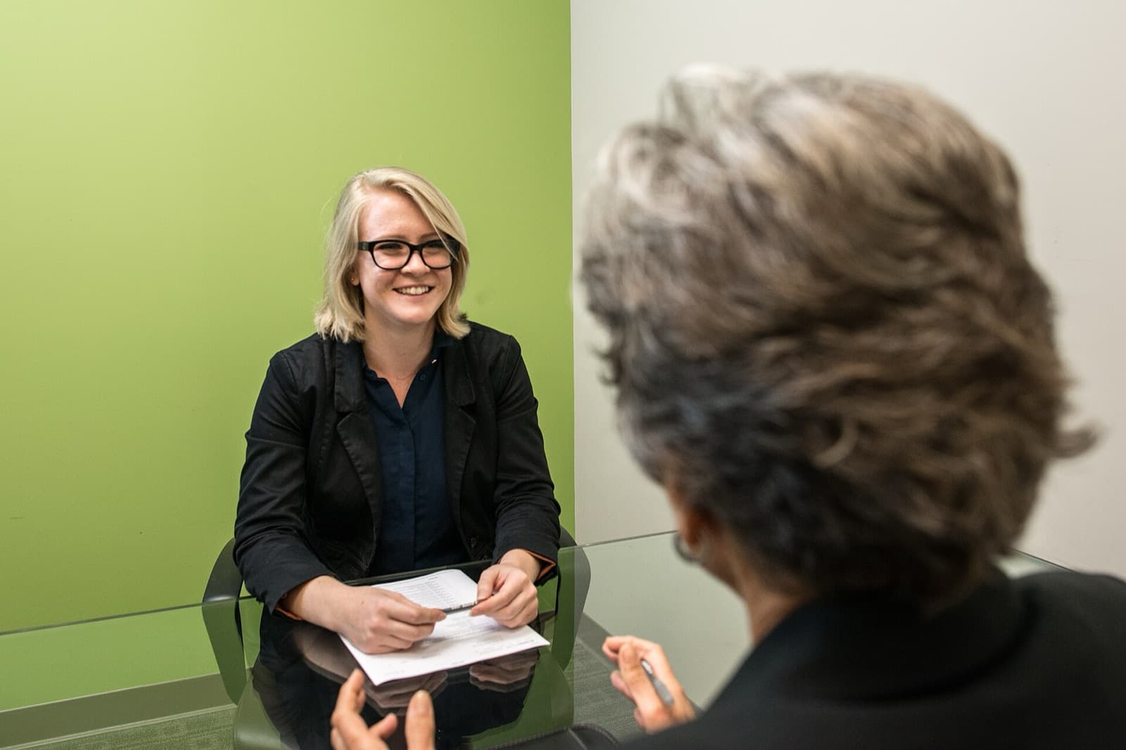 A candidate smiling as she answers an interviewer across a table