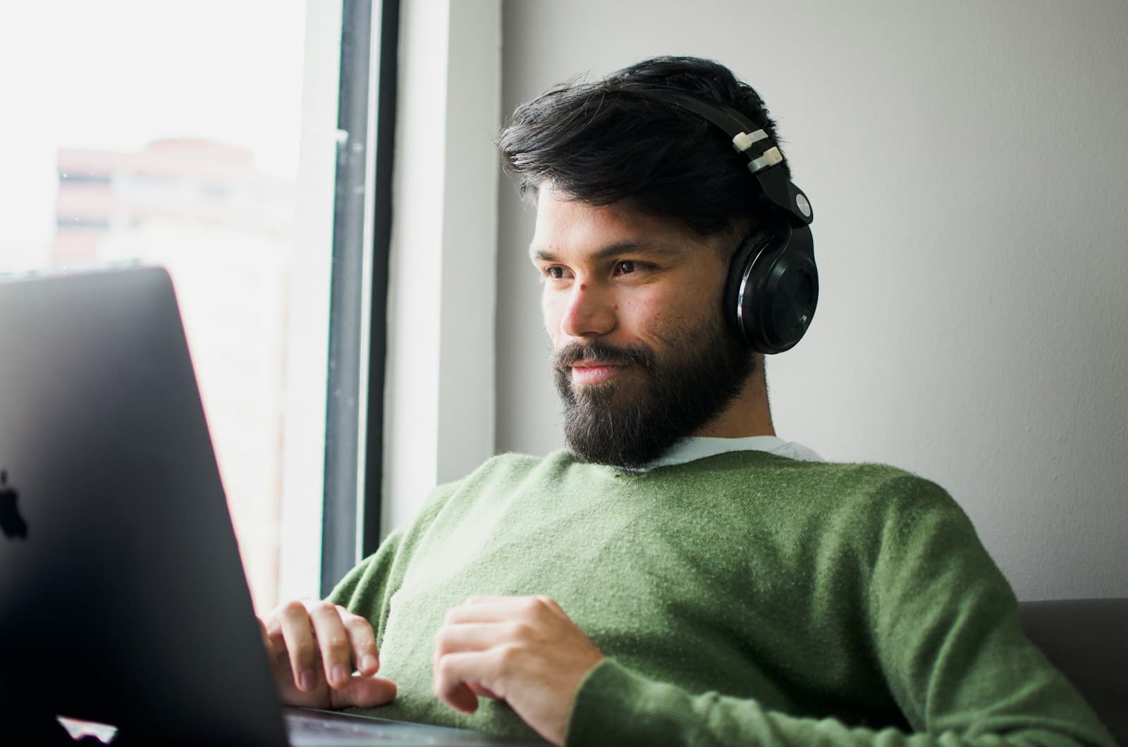 A man in headphones answering at his laptop